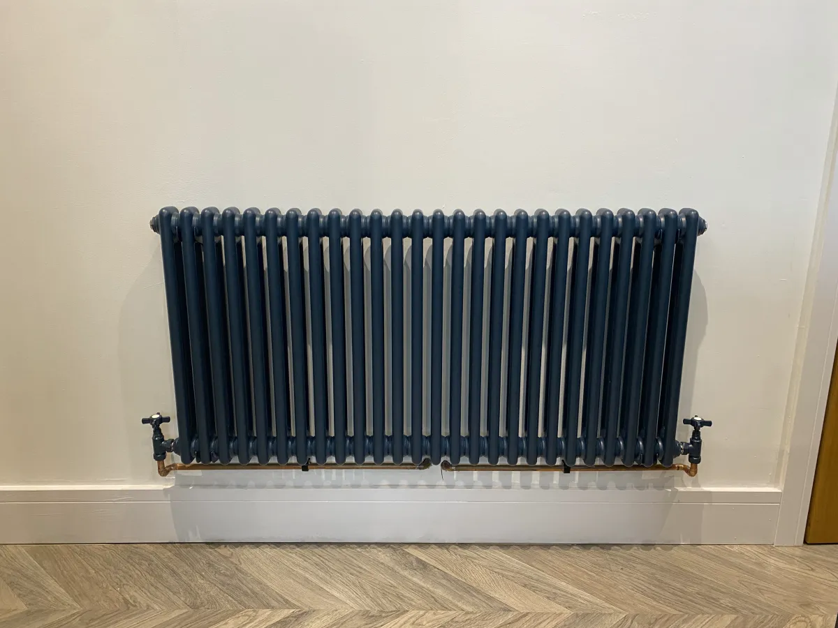 Anthracite column radiator fitted to a wall with new copper pipework and angled valves